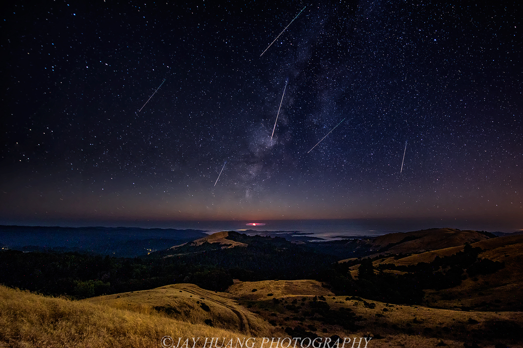 bright Perseid meteors streaking across a dark summer night sky